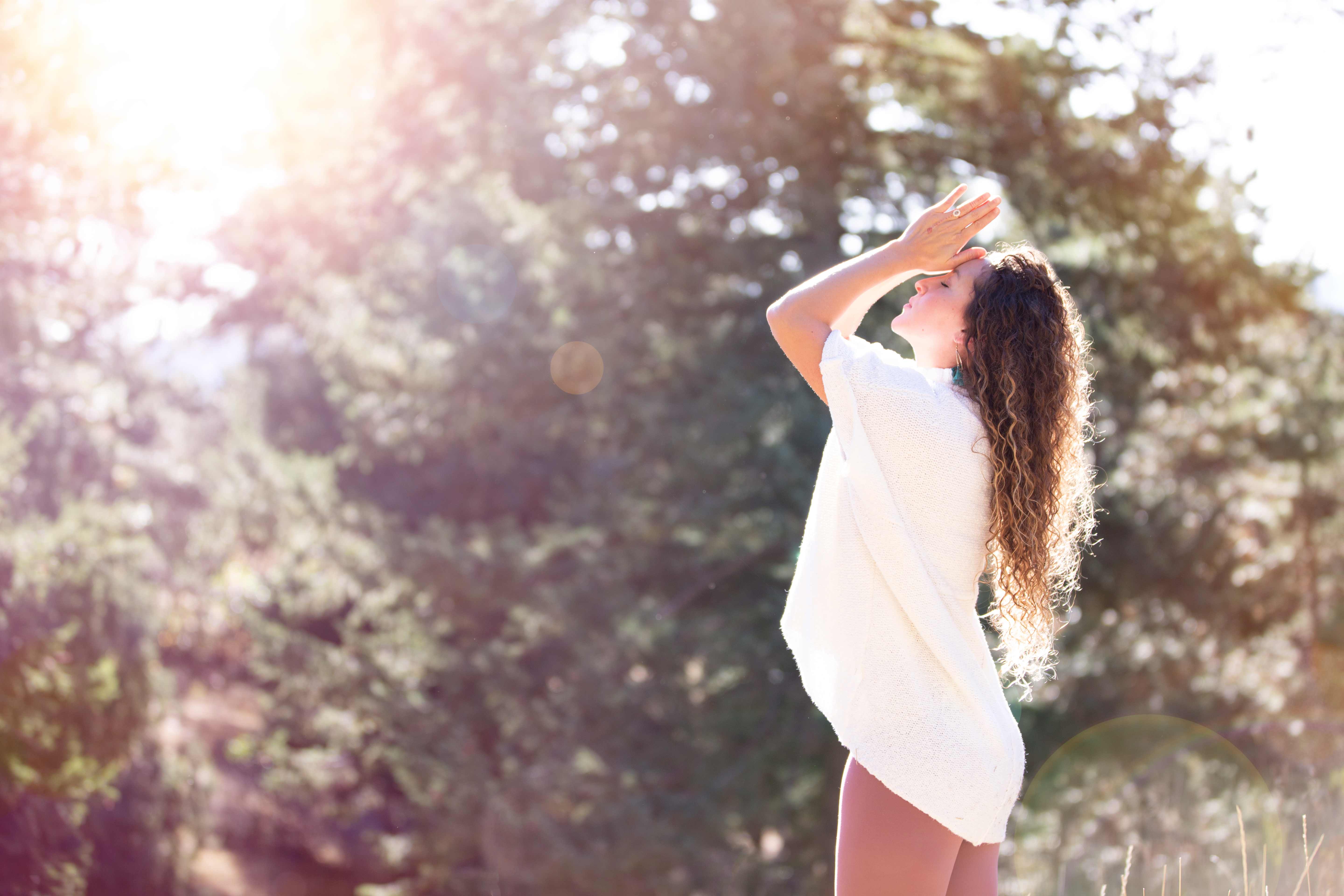 Woman turning toward warm sunlight in a peaceful forest meadow
